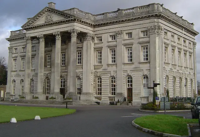 The pale stone front of Moor Park Mansion beside its landscaped grounds
